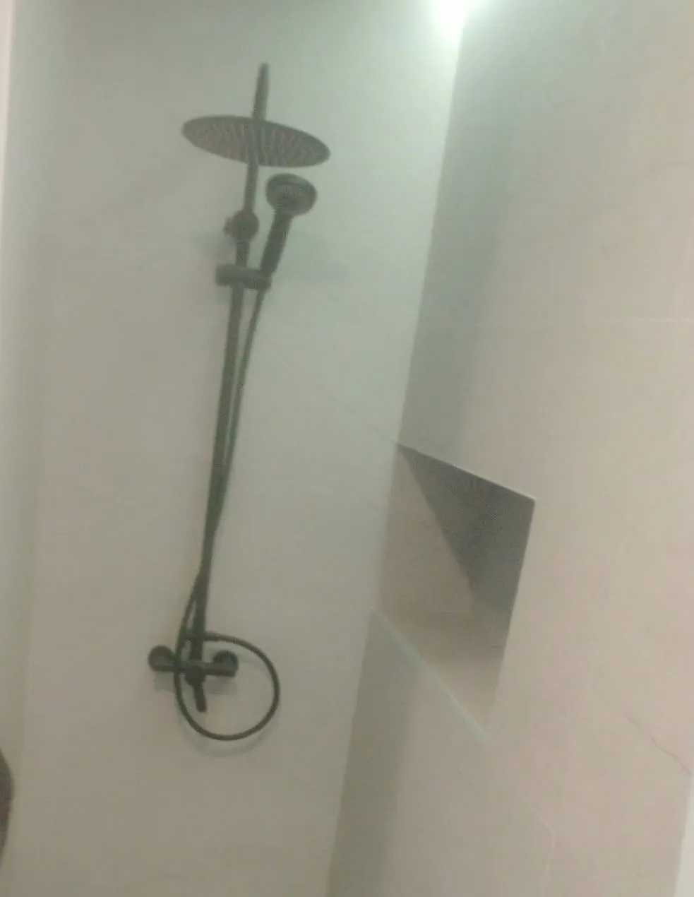 Ducha de obra terminada con grifería negra y hornacina en la pared