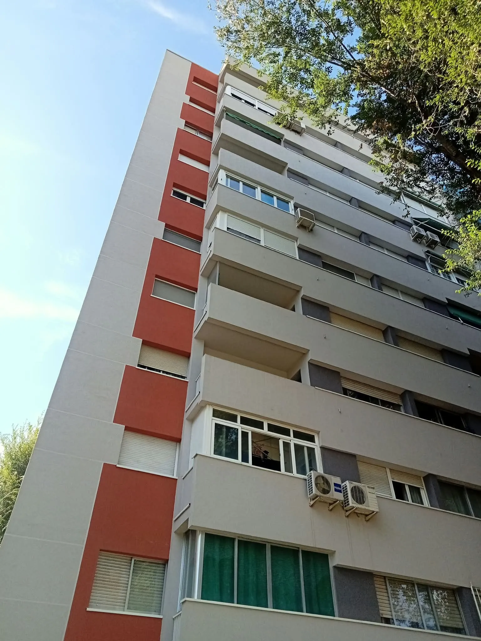 Fachada de un bloque de viviendas rehabilitada con monocapa gris y rojo