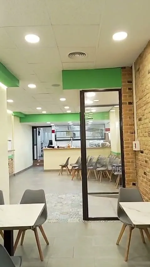 Comedor de un local con puertas de cristal y pared de ladrillo