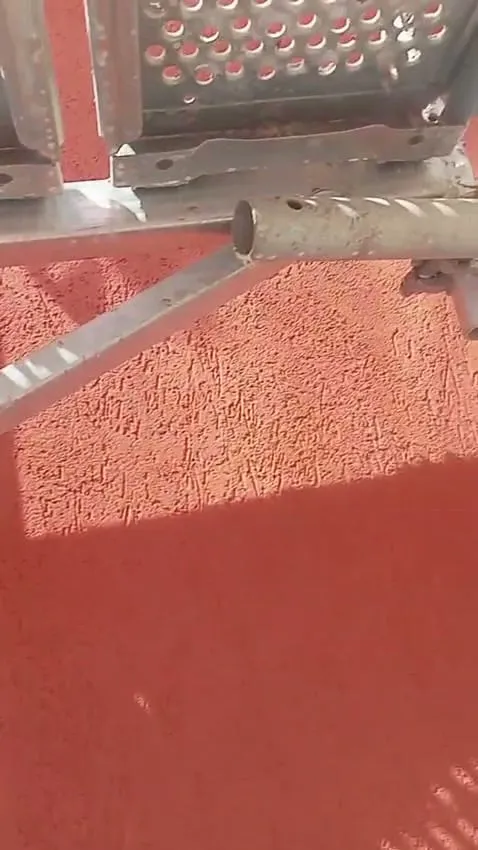 Aplicación de monocapa en rojo desde el andamio de una fachada